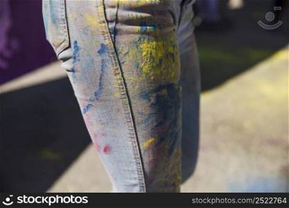 close up woman s jeans with holi color powder