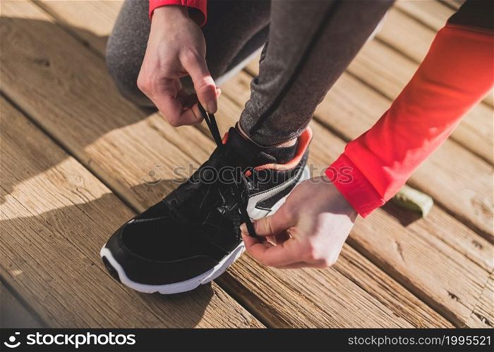 close up woman tying her shoelaces wooden floor