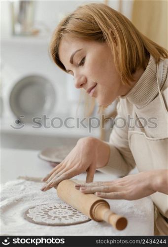 close up woman using rolling pin pottery