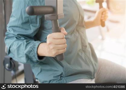 Close-up woman Weight training on machine exercise in gym. Athletic woman lifestyle is strength exercise.
