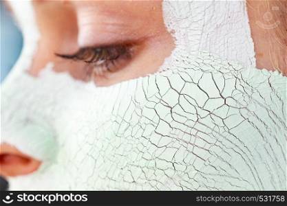 Close up woman with green mud mask on face, detail view. Teen girl have dry cracked cosmetic on skin. Beauty treatment. Skincare.. Girl with mud mask on face