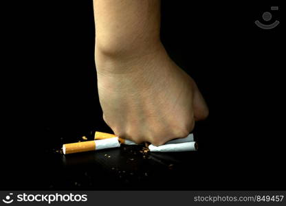 Close up women fist crushing cigarettes over black Background, World no tobacco day, STOP smoking