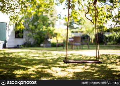 close up wooden swing under the tree in the garden, close up abstrack soft focus bokeh background on a colorful summer day with sunshine and shadows. close up wooden swing under the tree in the garden, close up abstrack soft focus bokeh background on a colorful summer day with sunshine