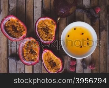 Close up yellow color passion fruit pulp and seed in small ceramic bowl isolated on BROWN board, andied fruit, plate with jam