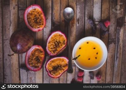 Close up yellow color passion fruit pulp and seed in small ceramic bowl isolated on BROWN board, spoon, candied fruit, plate with jam