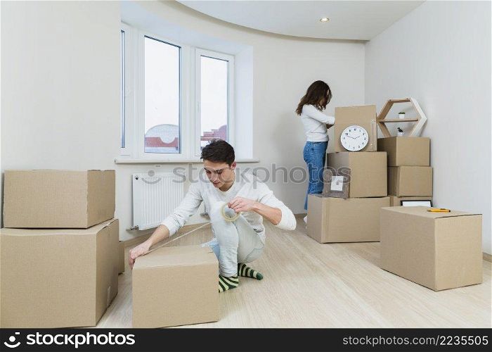 close up young couple packing cardboard box home