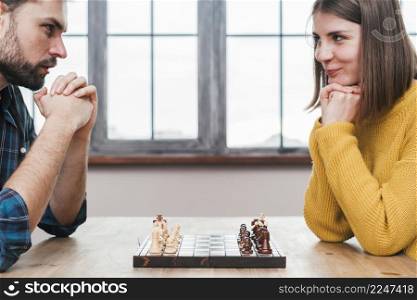 close up young couple with their hand clasped looking each other playing chess
