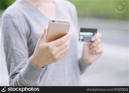 close up young female hands holding credit card and using mobile smart phone. Online shopping purchase Sell or Payment. Technology Pay online finance concept.