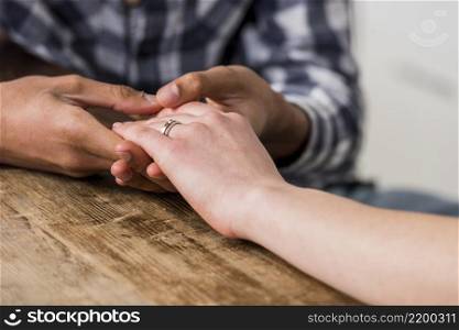 close up young man holding hand his girlfriend wooden desk
