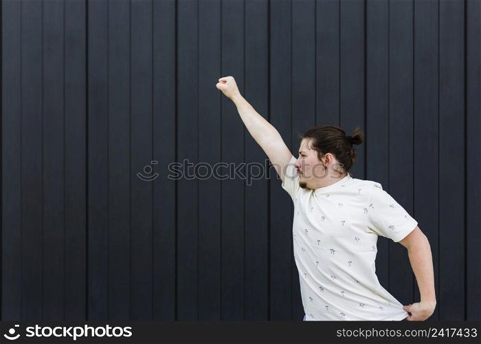 close up young man raising his arms against black wall