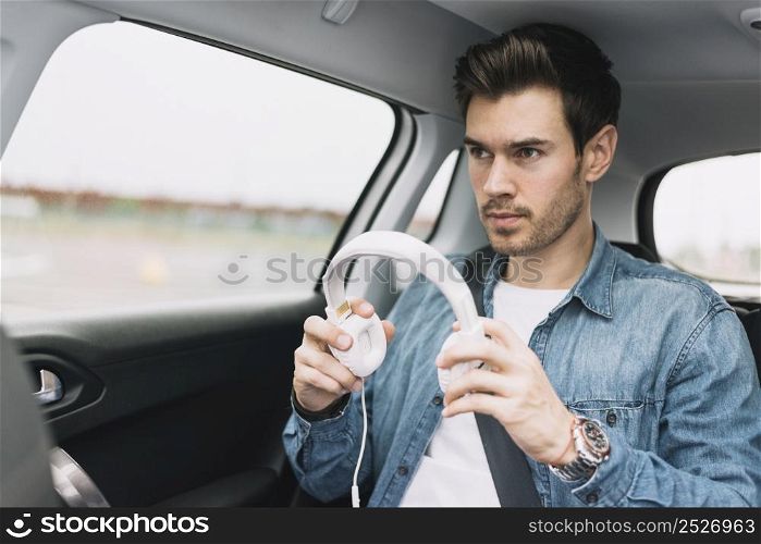 close up young man travelling car putting white headphone