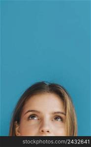 close up young woman s face looking up against blue backdrop