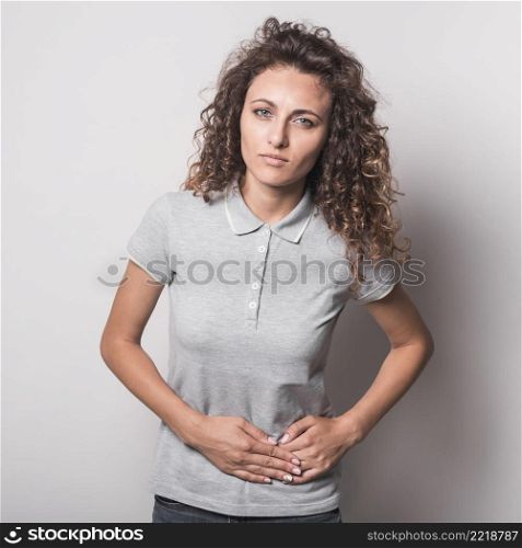 close up young woman suffering from stomach ache against gray background