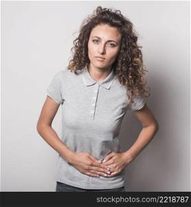close up young woman suffering from stomach ache against gray background