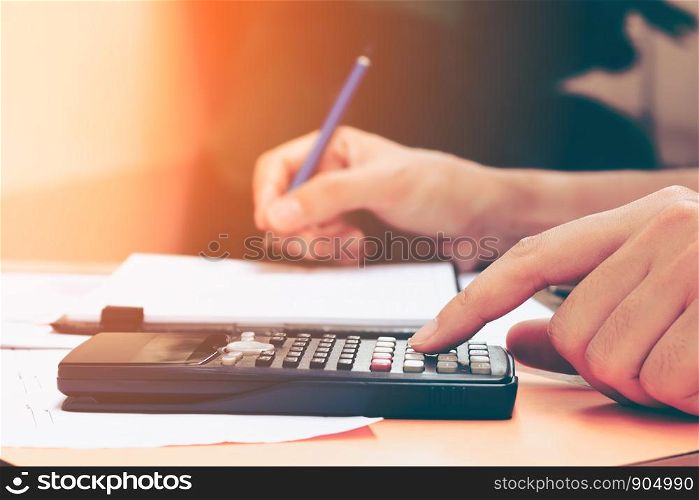 Close up young woman with calculator counting making notes at home, hand is writes in a notebook. Savings, finances, concept.