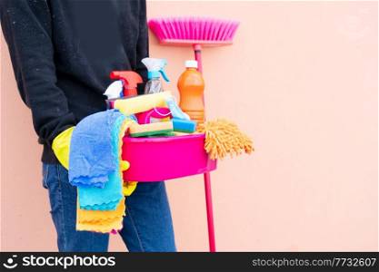 close-upof worker in gloves holding basin with cleaning supplies, spring clean concept. caucasian woman holding basin with cleaning supplies