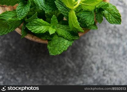 Close view of fresh mint leaves on a dark concrete background