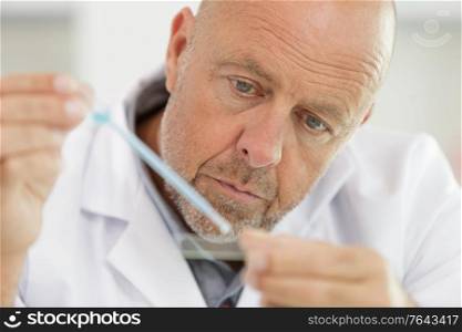 close view of senior male scientist using pipette