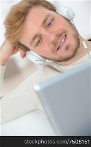close view of young man relaxing with laptop and headphones