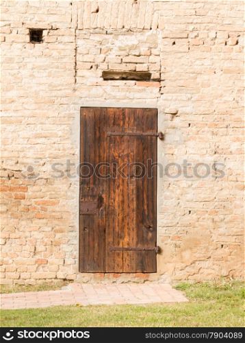 Closed antique wooden door on brick wall