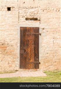 Closed antique wooden door on brick wall