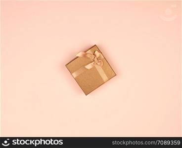 closed golden gift box with a bow on a beige background, top view, festive backdrop