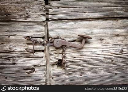 closed old wooden door with rusty chain