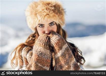 Closed portrait of young beautiful woman enjoying the snowy mountains in winter, in Sierra Nevada, Granada, Spain. Female wearing winter clothes.. Young woman enjoying the snowy mountains in winter