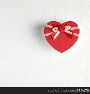 closed red heart-shaped box on a white textured surface, top view