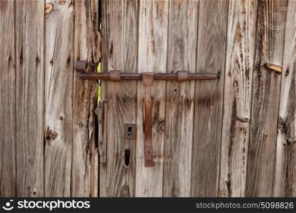 Closed rusty latch on an old wooden door