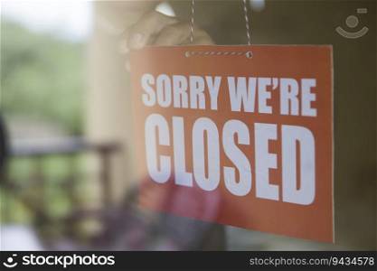 Closed sign board hanging on the glass door of cafe or small store