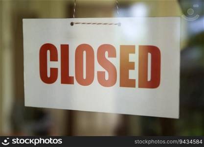 Closed sign board hanging on the glass door of cafe or small store