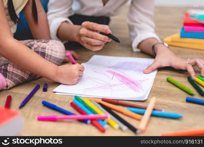 Closed up hands of mom teaching little children to drawing cartoon in art class with color pen. Back to school and Education concept. Family and Home sweet home theme. Preschool kids theme