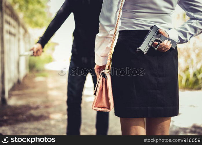 Closed up of woman hiding hand gun in back for fighting to robber or protect herself from stole her moneys or dangerous. Criminal and Sexual rape concept. News report and Economic downturn theme