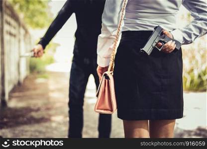 Closed up of woman hiding hand gun in back for fighting to robber or protect herself from stole her moneys or dangerous. Criminal and Sexual rape concept. News report and Economic downturn theme
