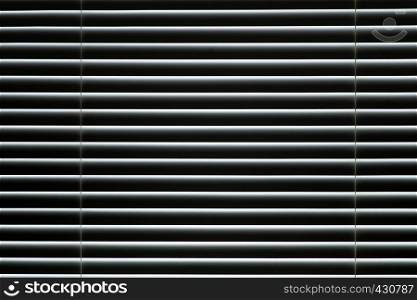 Closed window blinds. Light makes its way through closed blinds.. Plastic closed window blinds in the room.