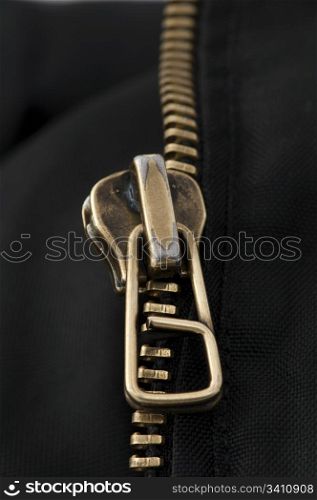 Closed yellow metal zipper. Black textured textile