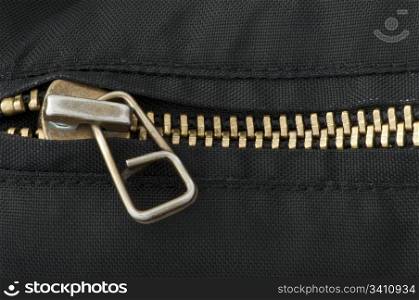 Closed yellow metal zipper. Black textured textile