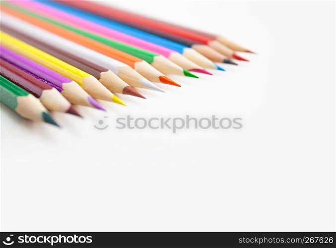 Closeup a row of colored pencils on white background with selective focus with copy space.
