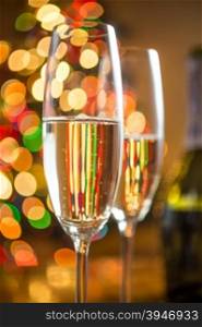Closeup abstract photo of two glasses with champagne against sparkling Christmas tree