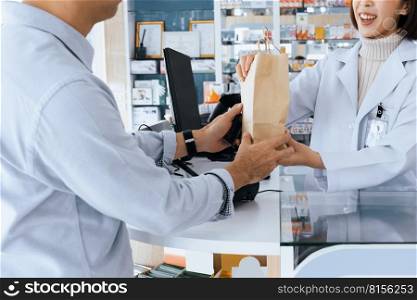 Closeup affable pharmacist give or handing customer a bag of qualified medications or medical supply, customer service concept in pharmacy. Pharmacist talking to customer in drugstore counter.. Closeup affable pharmacist hand qualified medicine to customer in pharmacy.