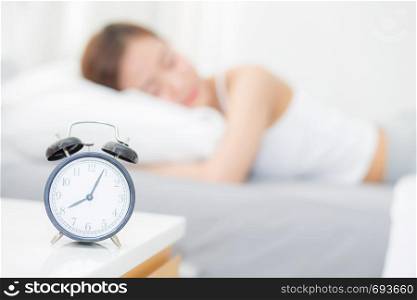 closeup alarm clock and beautiful asian young woman in morning, wake up for sleep with alarm clock, relax and lifestyle concept.