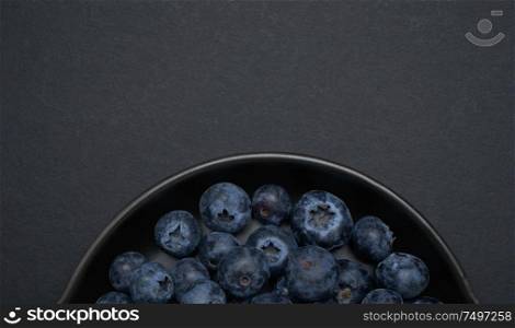 Closeup and crop Blueberries on a black clay pan with black background