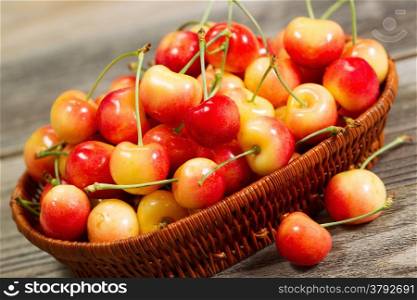 Closeup angled horizontal view of fresh Rainier cherries in basket on rustic wood