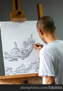 Closeup asian artist drawing black ink pen on white canvas place on easel, concep art about transportation and city.