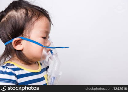 Closeup Asian face, Little baby girl sick her using steam inhaler nebulizer mask inhalation oneself on white background with copy space, health medical care