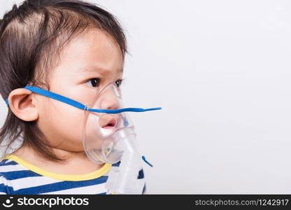 Closeup Asian face, Little baby girl sick her using steam inhaler nebulizer mask inhalation oneself on white background with copy space, health medical care