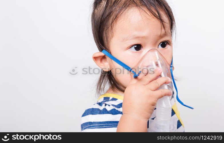 Closeup Asian face, Little baby girl sick her using steam inhaler nebulizer mask inhalation oneself on white background with copy space, health medical care