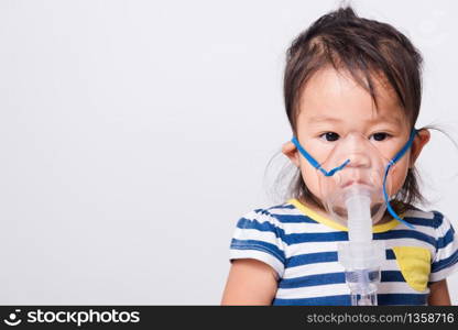 Closeup Asian face, Little baby girl sick her using steam inhaler nebulizer mask inhalation oneself on white background with copy space, health medical care