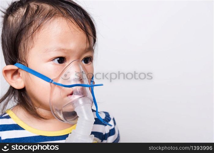 Closeup Asian face, Little baby girl sick her using steam inhaler nebulizer mask inhalation oneself on white background with copy space, health medical care